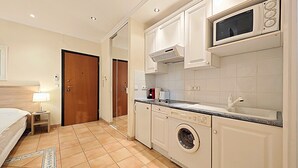 A compact kitchen with a microwave, washing machine, and a small countertop. - Studio Commandant André 13 by Viva Riviera (Cannes)