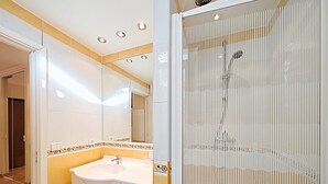A bathroom with a white sink, mirror, and tiled walls. - Studio Commandant André 13 by Viva Riviera (Cannes)