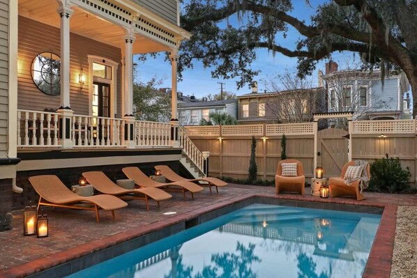 A pool area with lounge chairs and a covered porch.