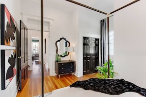 A bedroom with a bed, a dresser, a mirror, and a door.