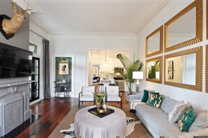 A living room with a fireplace, a television, a sofa, and a dining area with chairs.