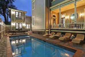 A swimming pool with lounge chairs and a covered patio area.