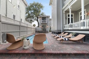 A poolside area with lounge chairs and a small table with a plant.