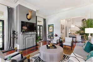 A spacious living room with a fireplace, a mounted deer head, a television, and a round coffee table.
