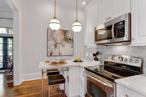 A kitchen with white cabinetry, stainless steel appliances, and pendant lighting.