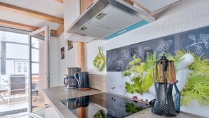 Een moderne keuken met een groot eiland, roestvrijstalen apparatuur en een prikbord met tekeningen van planten.