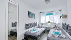 Een moderne slaapkamer met twee bedden, een nachtkastje, een spiegel en een raam met gordijnen.