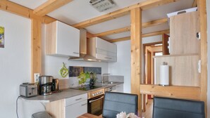 Een moderne keuken met houten balken, witte kasten, een eettafel met stoelen en een bloevas.