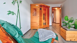 A sauna room with a wooden cabinet, a green couch, and a potted plant. - Ferienhaus Born by Interhome (Schwalenberg)