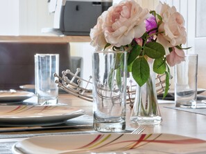 A dining table set with plates, glasses, and a vase with flowers.