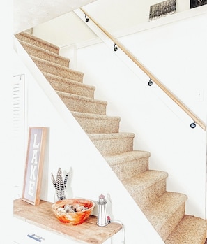 A staircase with a wooden handrail and carpeted steps.