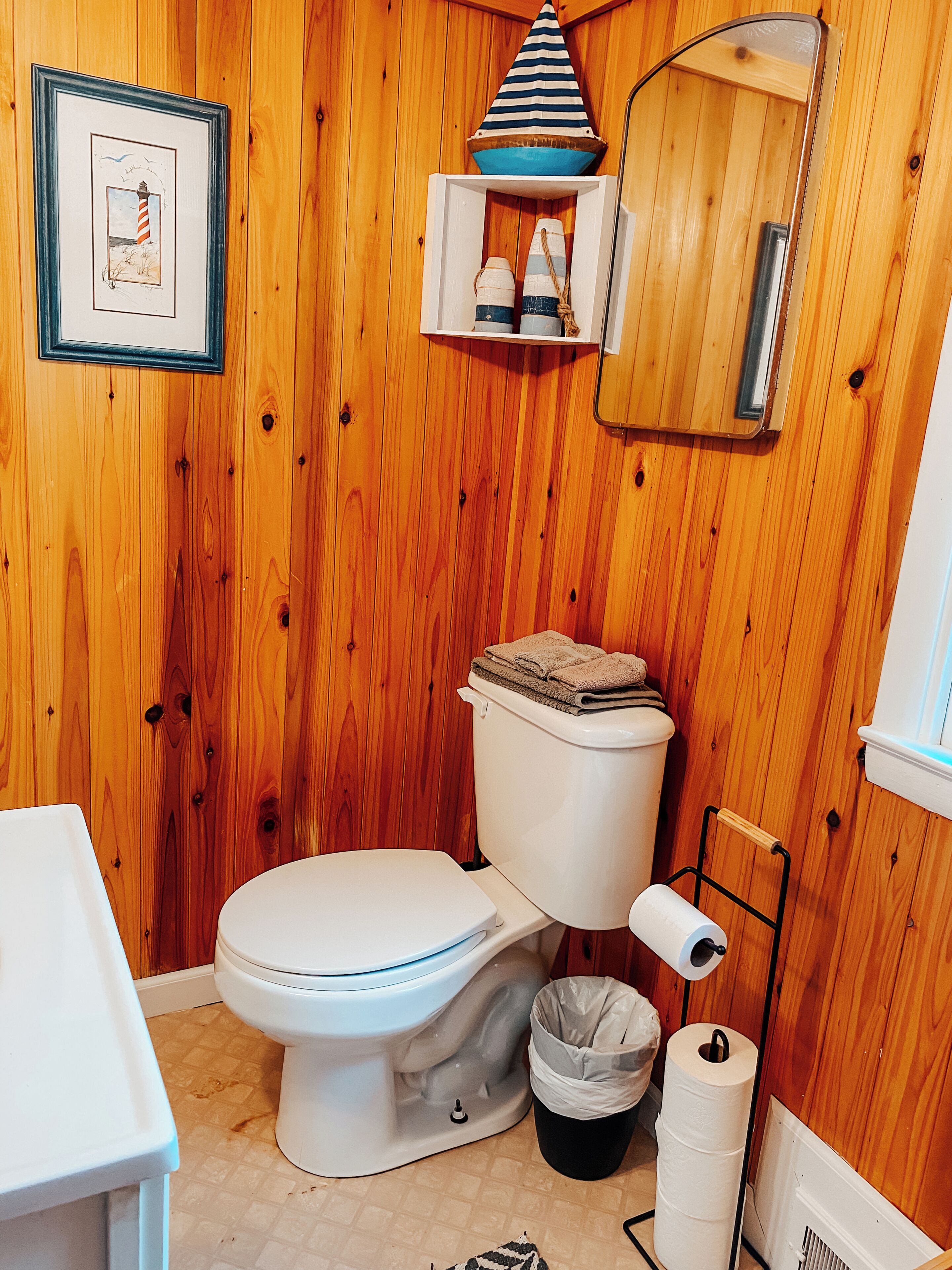 A wooden-paneled bathroom with a toilet, sink, and a framed picture on the wall.