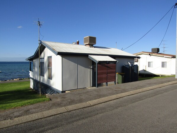 A small, single-story building with a metal roof, a garage door, and a visible chimney. - Classic Shack - Absolute Beachfront. Winter off peak special! (Point Turton)