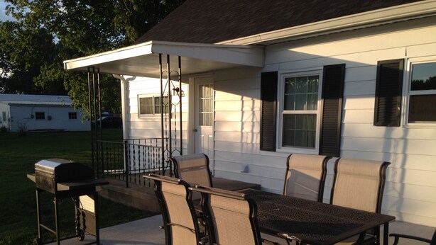 An outdoor patio with a table and chairs, a grill, and a covered area.
