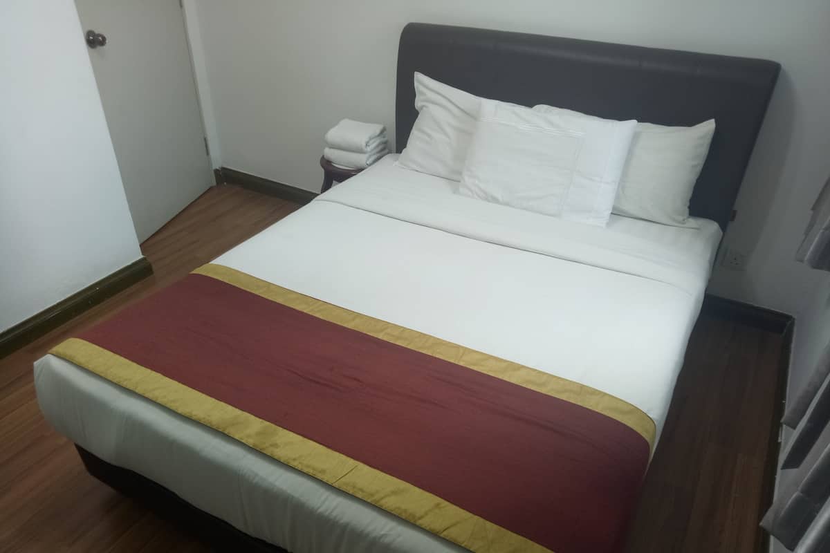 A neatly made bed with white linens and a red and yellow bedspread.