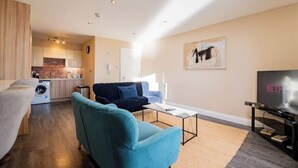 A modern living room with a sofa, a coffee table, and a TV. - Stylish Harbour View Apartment in a Private Building (Galway City)