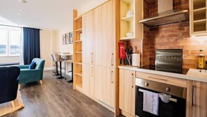 A modern kitchen with wooden cabinets, a stainless steel range hood, and a brick backsplash. - Stylish Harbour View Apartment in a Private Building (Galway City)