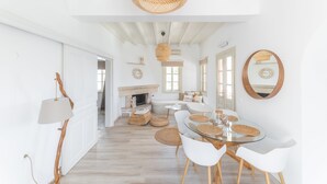 A spacious dining area with a round glass table, white chairs, and woven placemats. - Premium Pool Villa for 4 guests (Patmos)