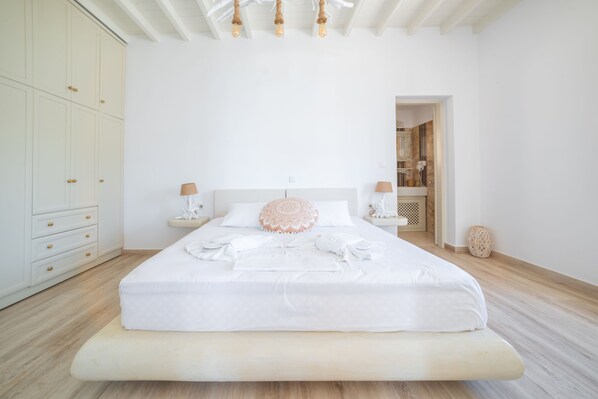 Een minimalistische slaapkamer met een groot bed, nachtkastjes en een kledingkast.