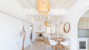 A bright, open-plan living space with a dining area, kitchen, and fireplace. - Premium Pool Villa for 4 guests (Patmos)
