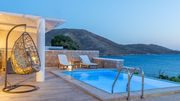A poolside area with a hanging chair, lounge chairs, and a view of the sea. - Premium Pool Villa for 4 guests (Patmos)