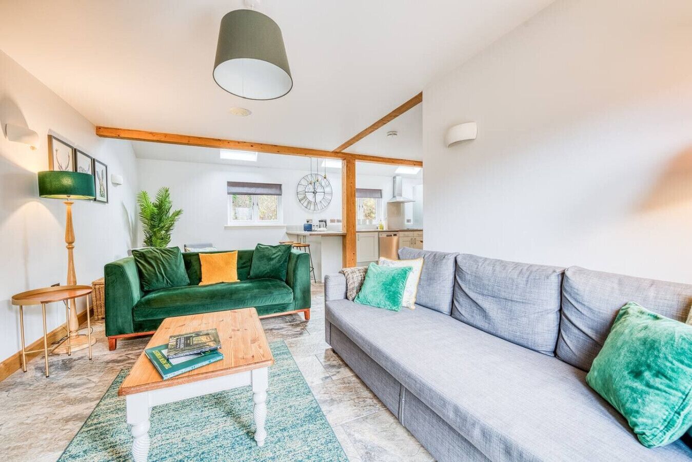 Ein modernes Wohnzimmer mit einem grünen Sofa, einem grauen Sofa, einem Holztisch und einer Stehlampe.