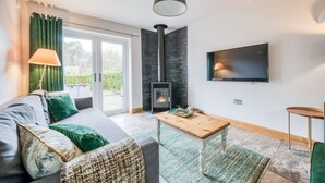 A modern living room with a sofa, a coffee table, a fireplace, and a TV mounted on the wall.