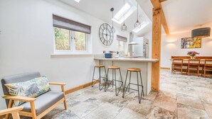 A modern kitchen with a central island, bar stools, and a dining area with wooden chairs.