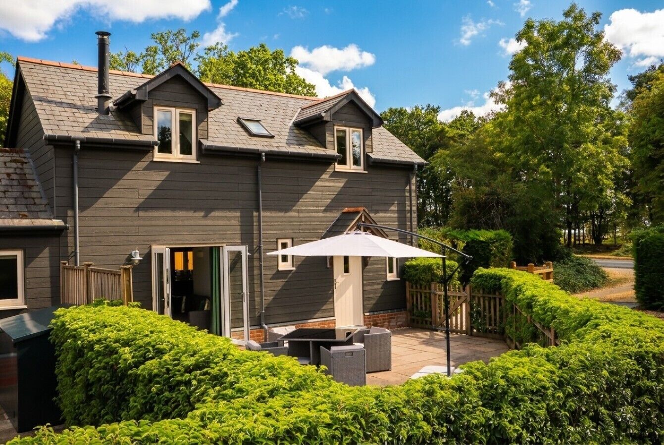 A two-story house with a patio area, a chimney, and a small window.