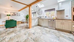 A modern kitchen with white cabinets, a built-in oven, and a skylight.