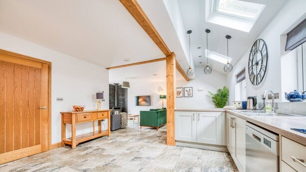 A spacious kitchen with white cabinets, a wooden dining table, and a large window.
