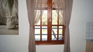 Ein Zimmer mit Fenster, Stuhl und einem an der Wand hängenden Bild.
