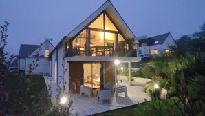 Uma casa moderna com uma varanda grande, uma área de refeições e um interior bem iluminado.