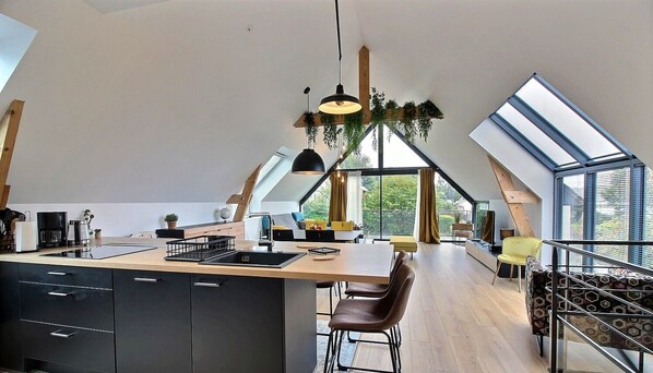 A modern kitchen with a central island, black cabinetry, and a large window.