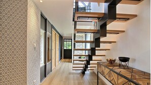 Um interior moderno com escada, soalho de madeira e parede estampada.