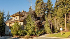 A two-story house with a sloped roof, surrounded by dense evergreen trees. - Luxury 4BR - Private HT, Ski In/Out, Free Parking (Whistler)