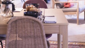 Ruokailutila, jossa on kahdelle katettu pöytä, tuoli, maljakko kukkineen ja peili seinällä.