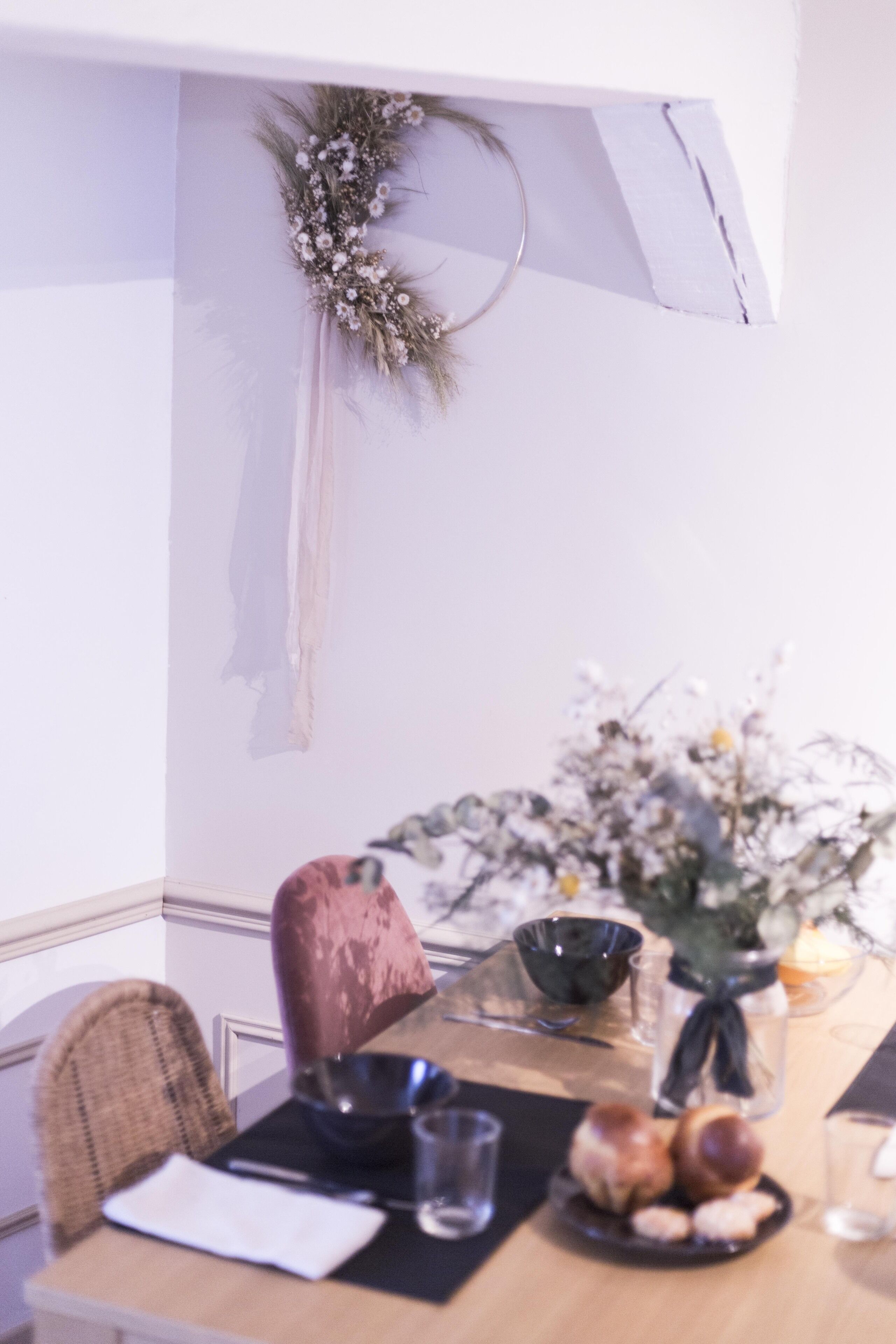 Une table à manger ornée d’un centre de table floral, d’un vase et d’une assiette de pain.