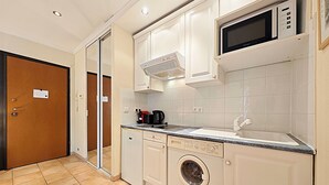 A compact kitchen with a microwave, a coffee maker, and a washing machine.