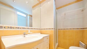 A bathroom with a white sink, a mirror, and a shower enclosure.