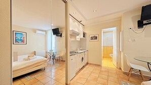 A compact living space with a bed, kitchenette, and a small dining area.