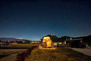 A rustic cabin with a large window, a porch, and a mountain backdrop. - Twin Dome Ryugu (Hokuto)