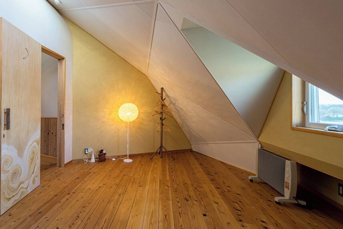 A room with wooden flooring, a standing lamp, a radiator, and a window with a view.