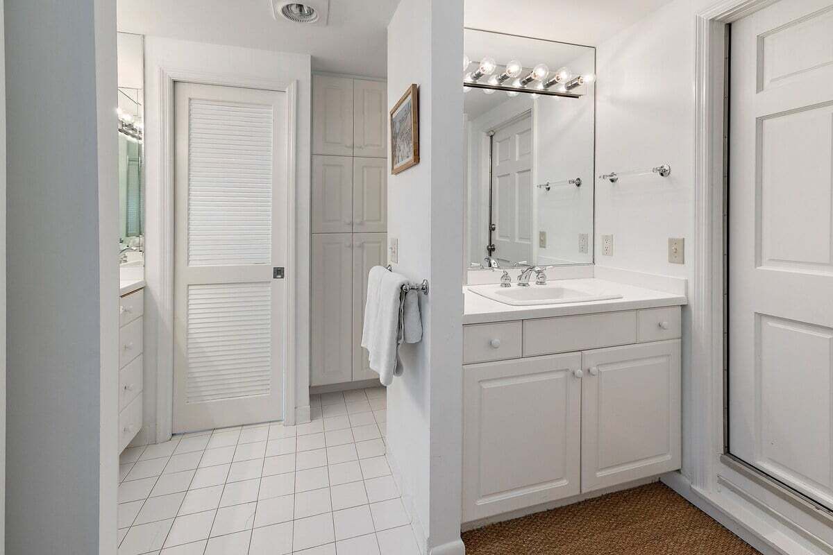 A bathroom with white cabinetry, a vanity with a mirror, and a towel rack.