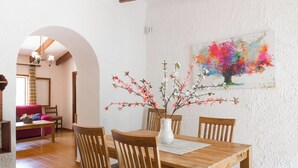 A dining area with a wooden table and chairs, a vase with flowers, and a colorful painting on the wall. - Can Company - Beautiful finca with pool and garden in Campanet (Campanet)