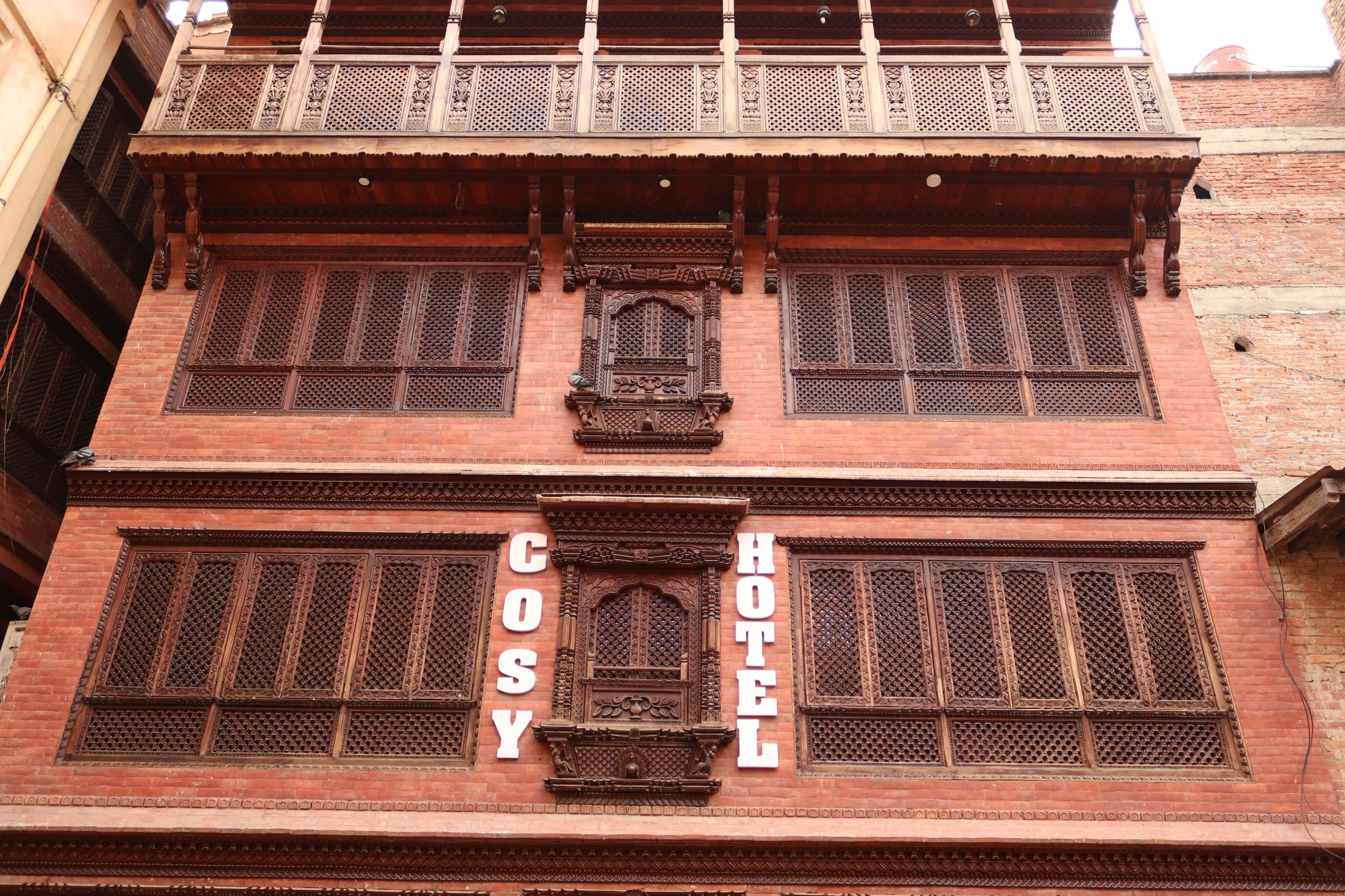A traditional building with a sign reading "Cosy Hotel".