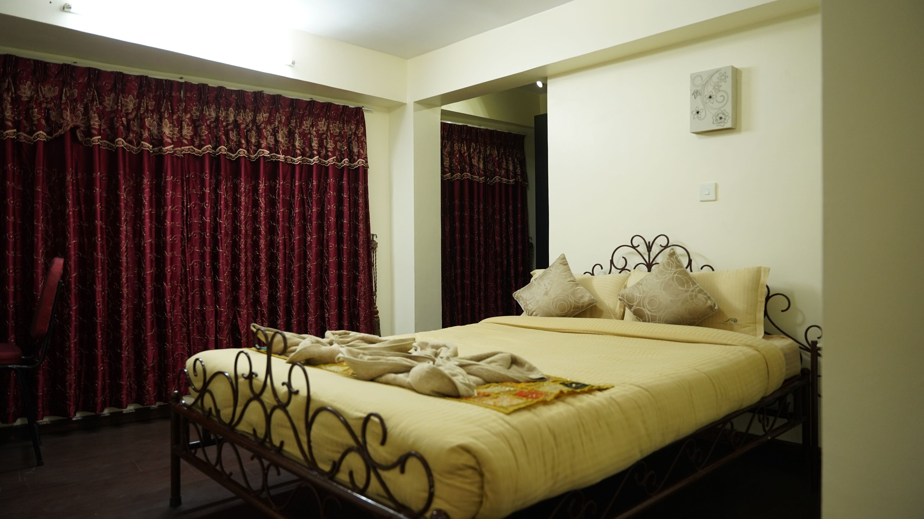 A bedroom with a bed, curtains, and a mirror.