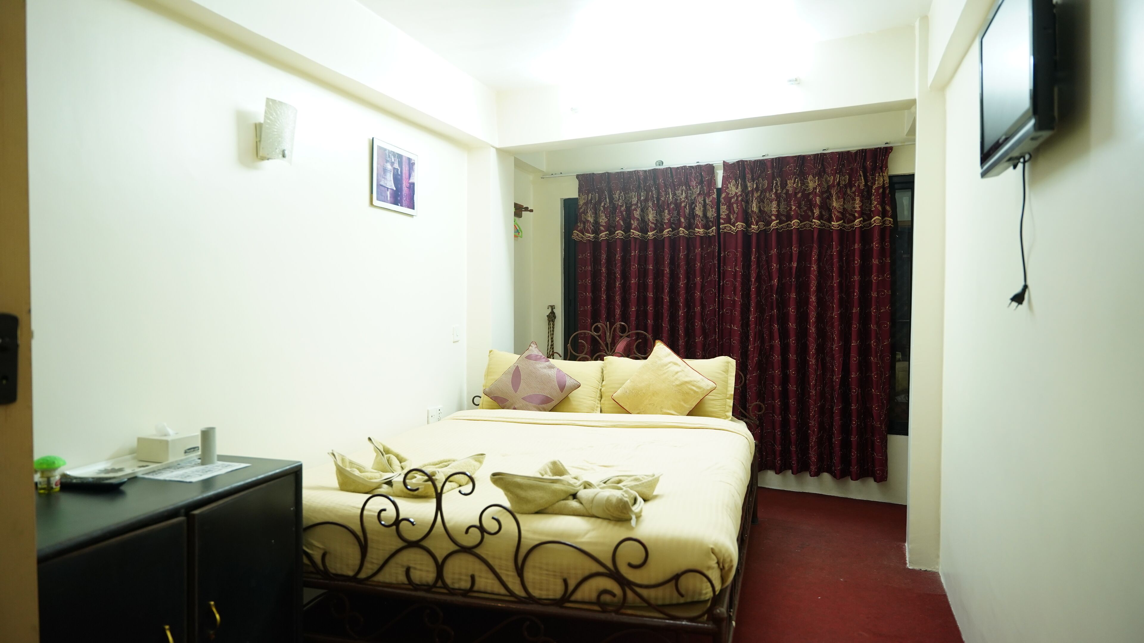 A hotel room with a bed, a desk, a television, and a window with curtains.