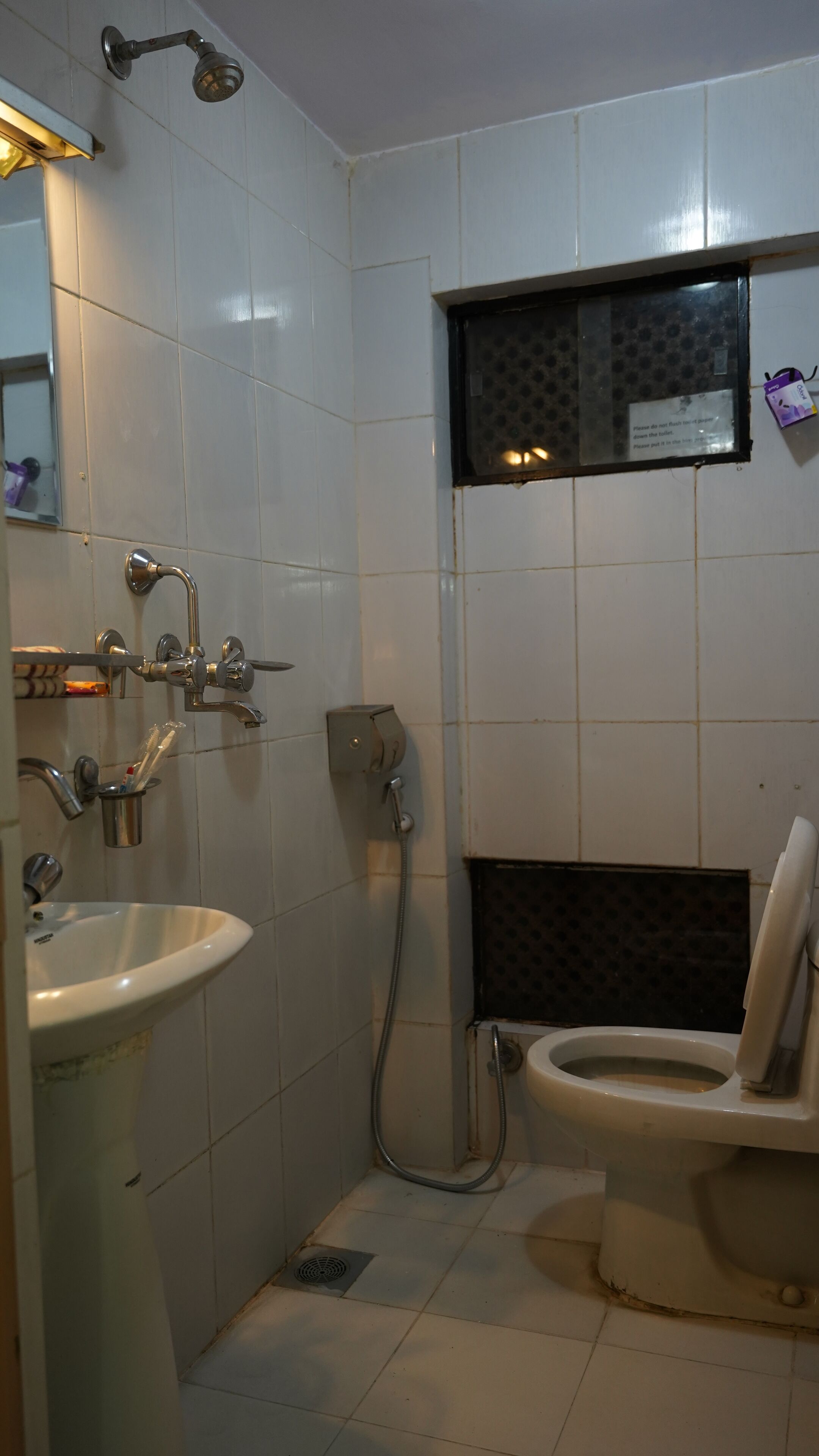 A small, tiled bathroom with a sink, toilet, and shower.