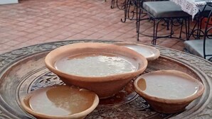 A terrace with tables and chairs, a sign for a hotel, and a decorative tray with bowls. - Cosy Hotel (Bhaktapur)